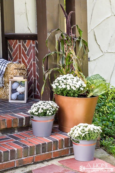 I love this neutral fall porch with white mums and shades of gray and copper! You'll want to pin this one!