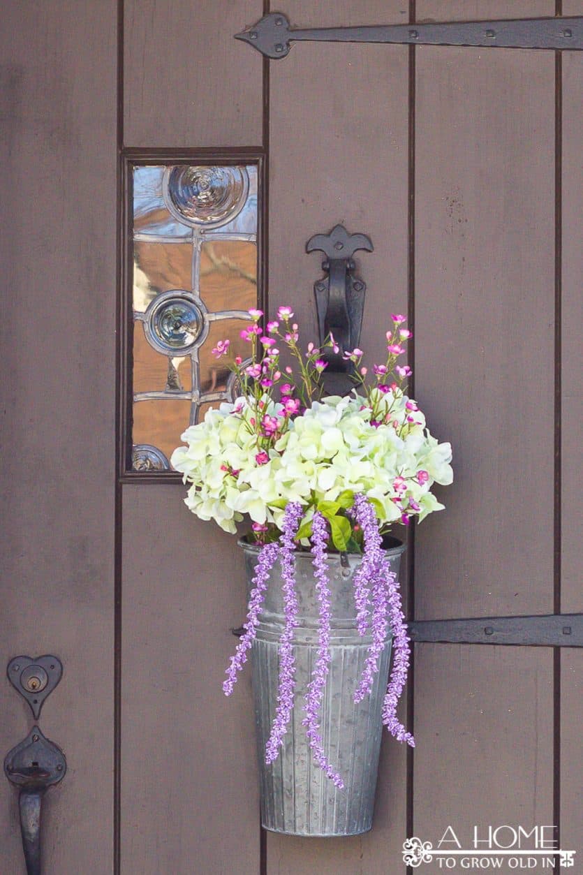 This spring floral door hanger is so easy to do and requires no floral arranging skills! A flower arrangement is a fun alternative to a wreath! Plus, I love the galvanized bucket!