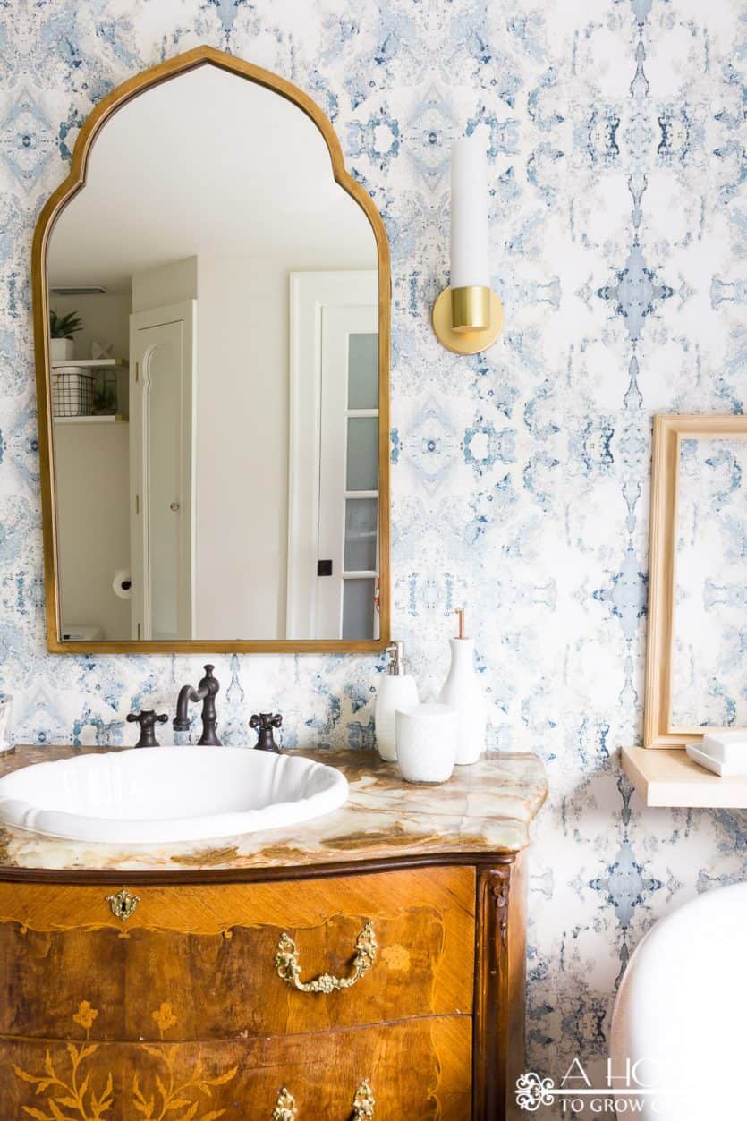 modern bathroom makeover with Anthropology wallpaper and an antique vanity