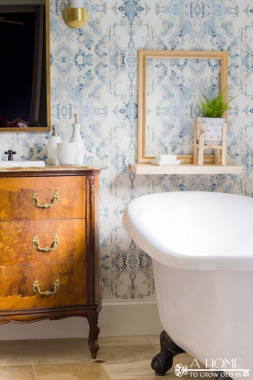 modern bathroom makeover with Anthropology wallpaper, clawfoot bathtub and an antique vanity