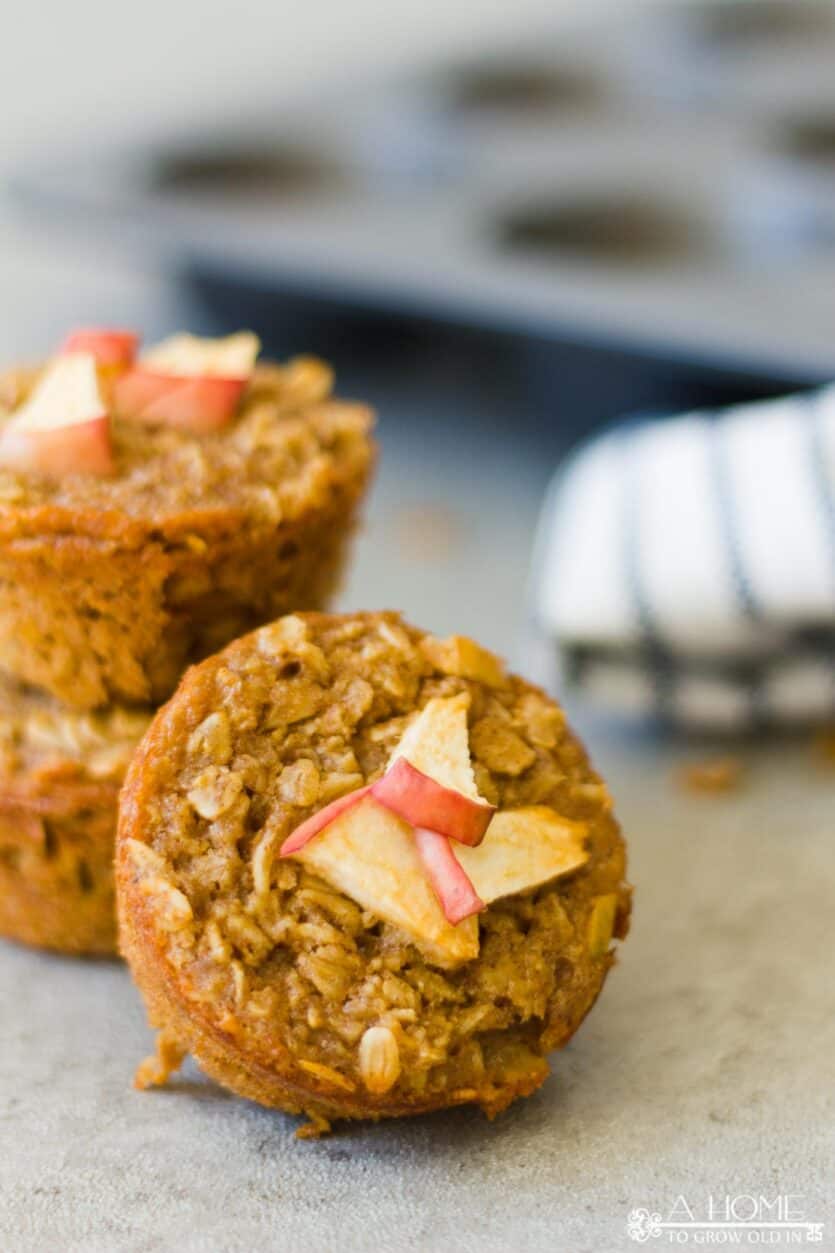 Three cinnamon apple oatmeal muffins with a towel in the background