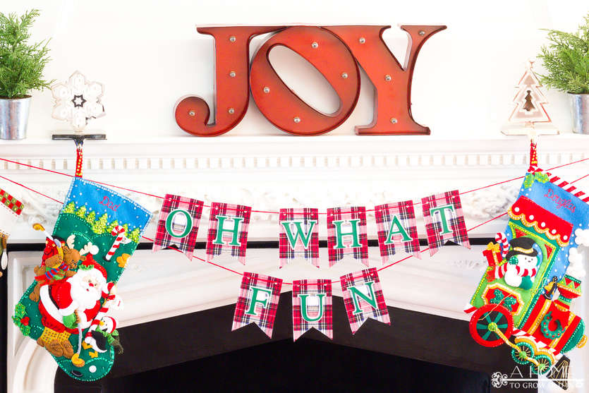 Oh What Fun DIY fabric Christmas banner hanging from a fireplace mantle with Christmas stockings