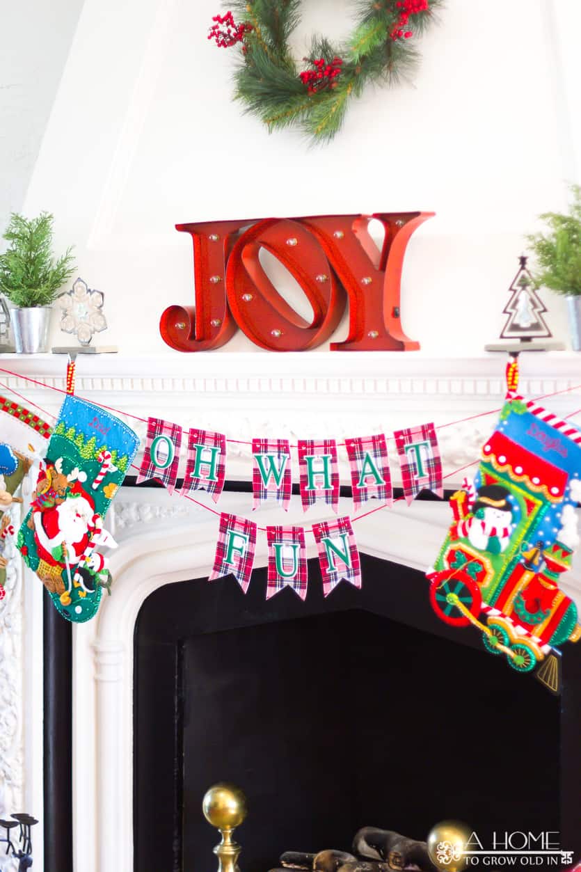 Oh What Fun DIY fabric Christmas banner hanging from a fireplace mantle with Christmas stockings