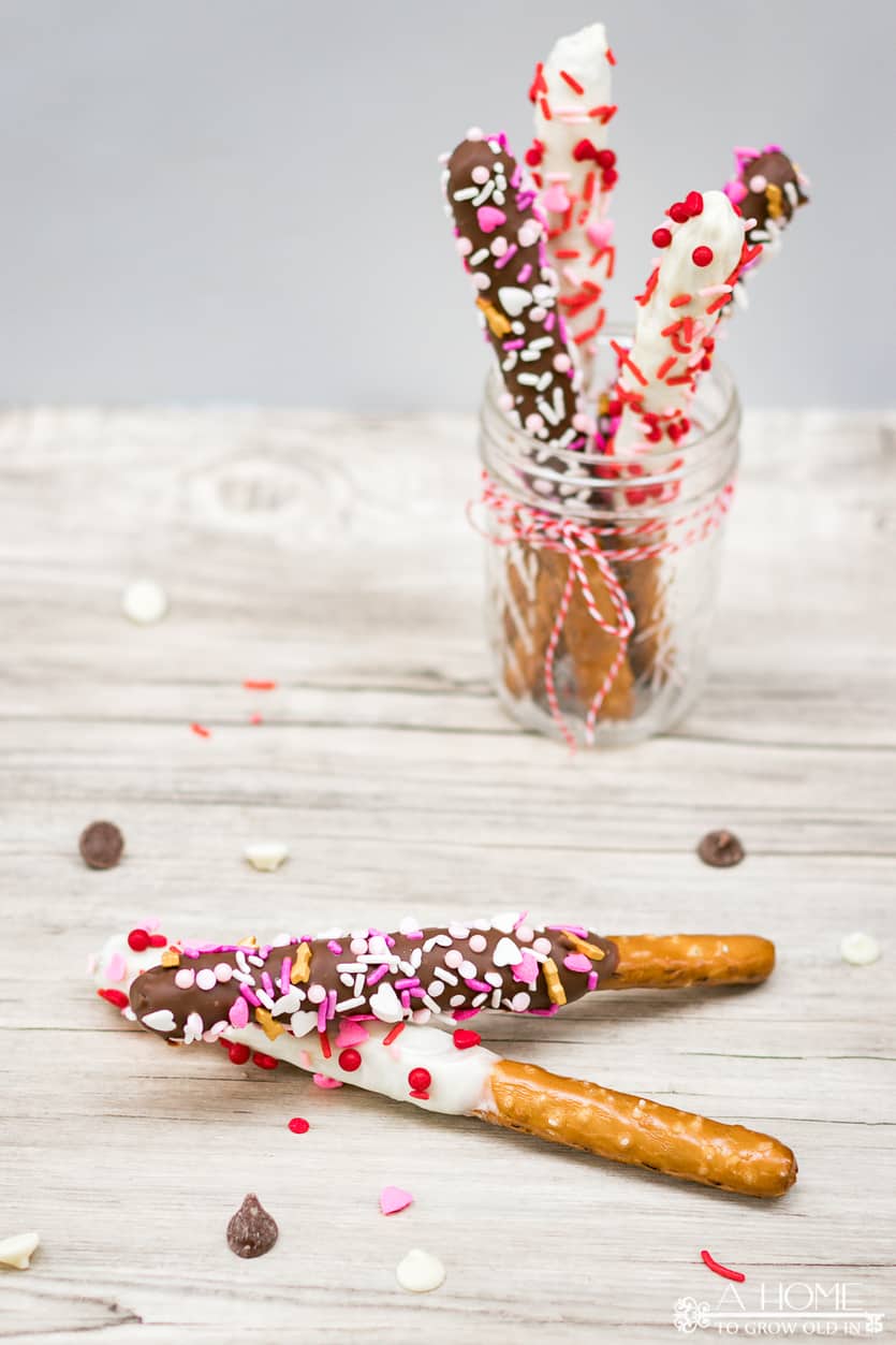white chocolate and milk chocolate covered pretzel rods with valentines day sprinkles in a mason jar